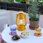 Feuerhand LED Laterne Baby Special 276 auf einem Tisch mit Snacks und Pflanzen, ideal für stimmungsvolles Licht.