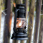 Feuerhand Baby Special 276 Sturmlaterne an einem Holzpfahl im Freien, strahlendes Licht sichtbar.