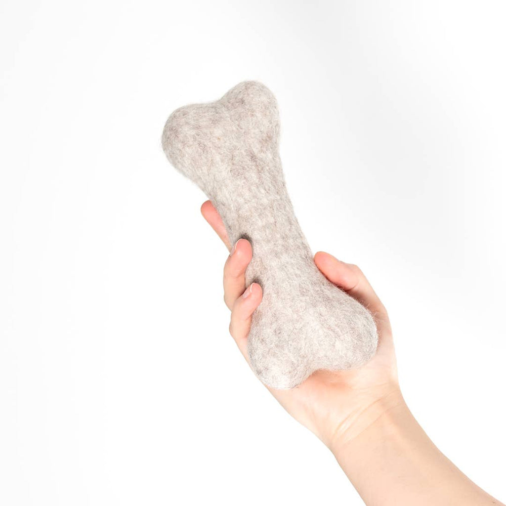 Hundespielzeug aus Schafwolle Knochen in einer Hand gehalten, ideal für Hunde zum Spielen und Apportieren.