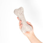 Hundespielzeug aus Schafwolle Knochen in einer Hand gehalten, ideal für Hunde zum Spielen und Apportieren.