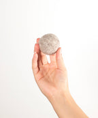 Hundespielzeug aus Schafwolle in Hand gehalten, leichter Wollball für Hunde, beige.