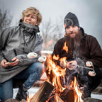 Zwei Personen rösten mit einem Lagerfeuer-Spieß Marshmallows über dem offenen Feuer.
