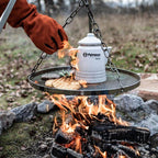 Hänge-Rost für Dreibein mit Grillgut über offenem Feuer, ideal für rustikale Grillabende im Freien.