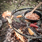 Hänge-Rost für Dreibein mit saftigem Steak, Gemüse und Bohnen über dem offenen Feuer.