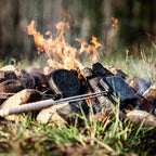 Sandwicheisen über einem Lagerfeuer, ideal zum Toasten von Snacks und Bagels in der Natur.