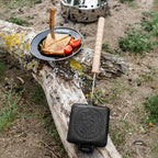 Sandwicheisen mit knusprigem Toast und Tomaten auf einem Holzstamm in der Natur.