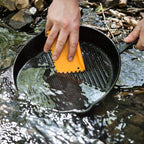 Schaber Feuertöpfe & Pfannen: Reinigung eines gusseisernen Pfannens in fließendem Wasser mit einem Schaber.