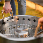 Tragegriff für Tyropit und Pyron, Benutzer trägt den Grill mit ergonomischen Griffen.