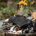 Waffeleisen auf einem Lagerfeuer, bereit zum Backen von köstlichen Waffeln im Freien.