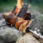 Stockbrot Spieß mit Gusseisenspitze hält frisch gebackenes Stockbrot über offenem Feuer.