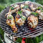 Atago Grillrost Durchmesser 34 cm mit gegrilltem Hähnchenfleisch und Rosmarin auf einem Grillrost.