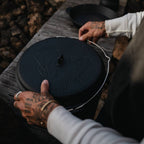 Feuertopf - Essential Line lid being handled, showcasing its robust design for outdoor cooking.