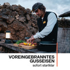 Mann bereitet Zutaten in einem Feuertopf (Dutch Oven) zum Kochen am offenen Feuer vor.