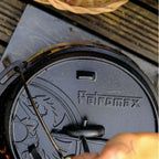 Petromax Feuertopf (Dutch Oven) mit Gusseisen-Deckel auf einem Holztisch.