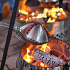 Ein Petromax Popcornmaker über offenem Feuer, ideal für Lagerfeuer-Snacks.