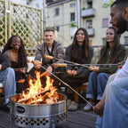 Freunde rösten Stockbrot Spieß mit Gusseisenspitze über einem offenen Feuer in einem urbanen Umfeld.