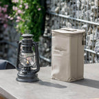 Transporttasche für Baby Special 276 neben einer Feuerhand Sturmlampe auf einem Tisch im Freien.